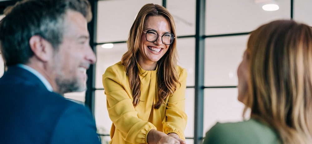Businessfrau begrüßt Frau, die mit dem Rücken im Bild zu sehen ist