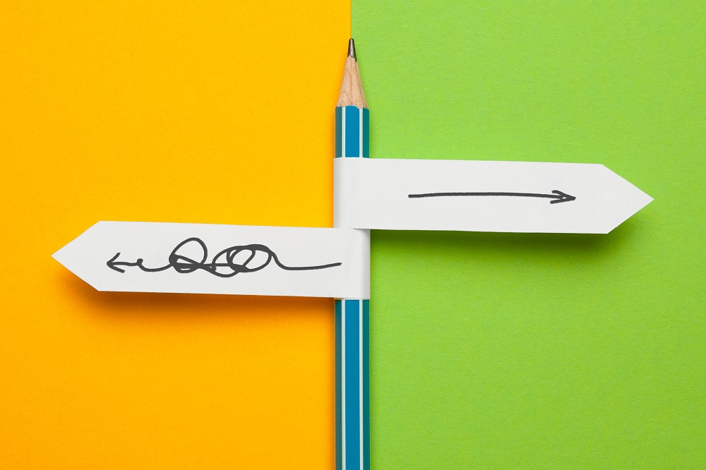 Bleistift mit zwei Papierfähnchen mit Pfeilen nach links mit Schleifen, nach rechts gerade