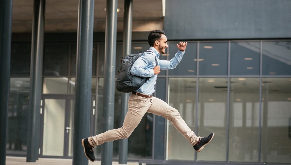 Mann hüpft über Treppe, Glaswand im Hintergrund