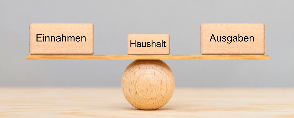 Einnahmen und Ausgaben im Haushalt im Gleichgewicht auf einer Holzkugel