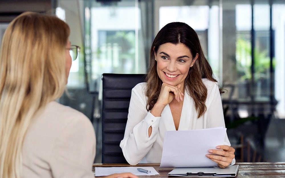 2 Frauen sitzen sich am Tisch gegenüber