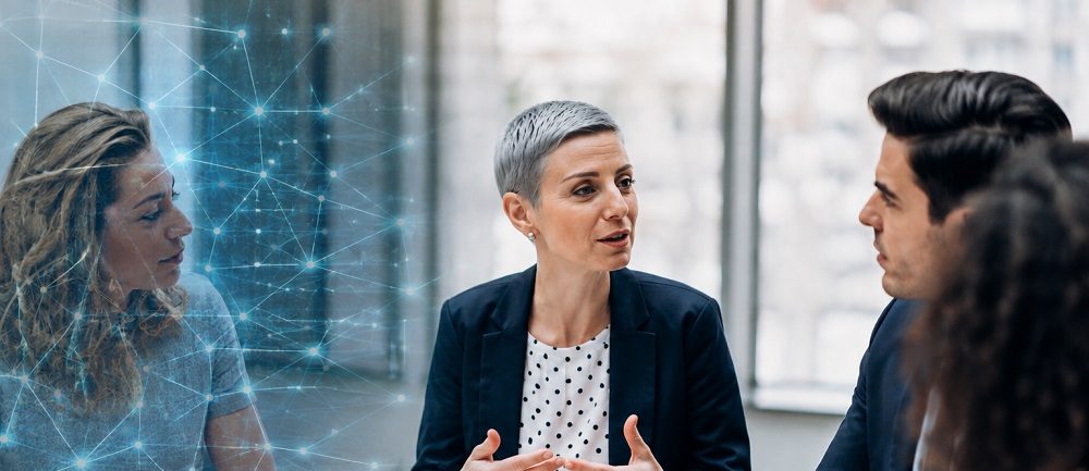 3 Personen im Gespräch, eine Frau überlappt ein digitales Netz